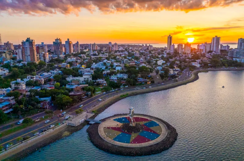 Costanera iluminada al atardecer sobre el río Paraná con reflejos dorados en el agua