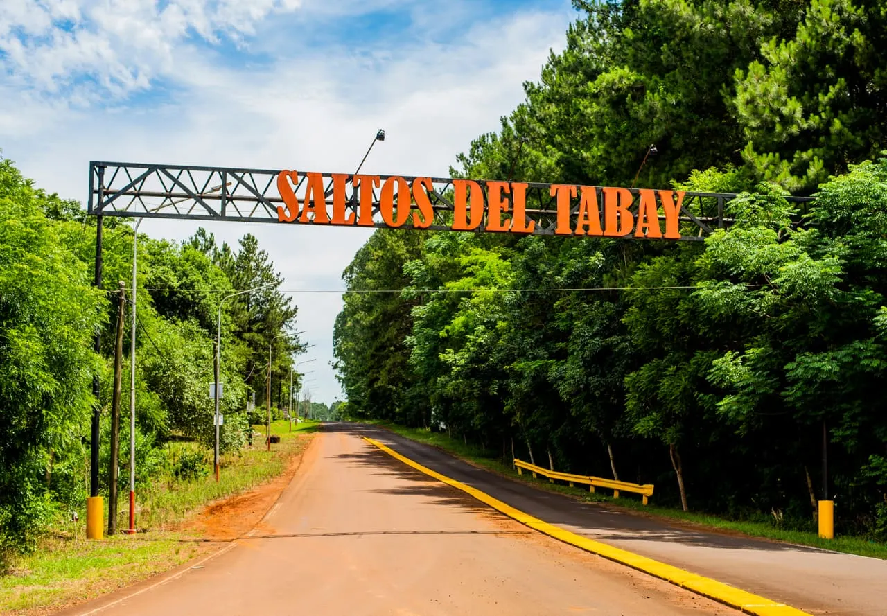 Cartel de entrada Saltos del Tabay sobre la ruta rodeada de arboledas